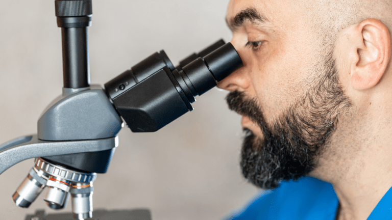 Pesquisador utilizando microscópio em laboratório, simbolizando nova chamada de propostas lançada pela FAPESP e NWO.