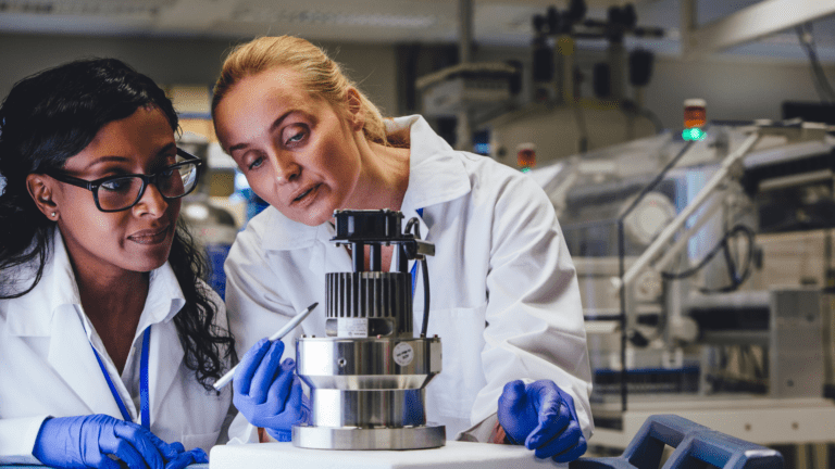 Duas pesquisadoras em laboratório analisando equipamento tecnológico, representando investimentos da Embrapii e BNDES na indústria de equipamentos médicos.