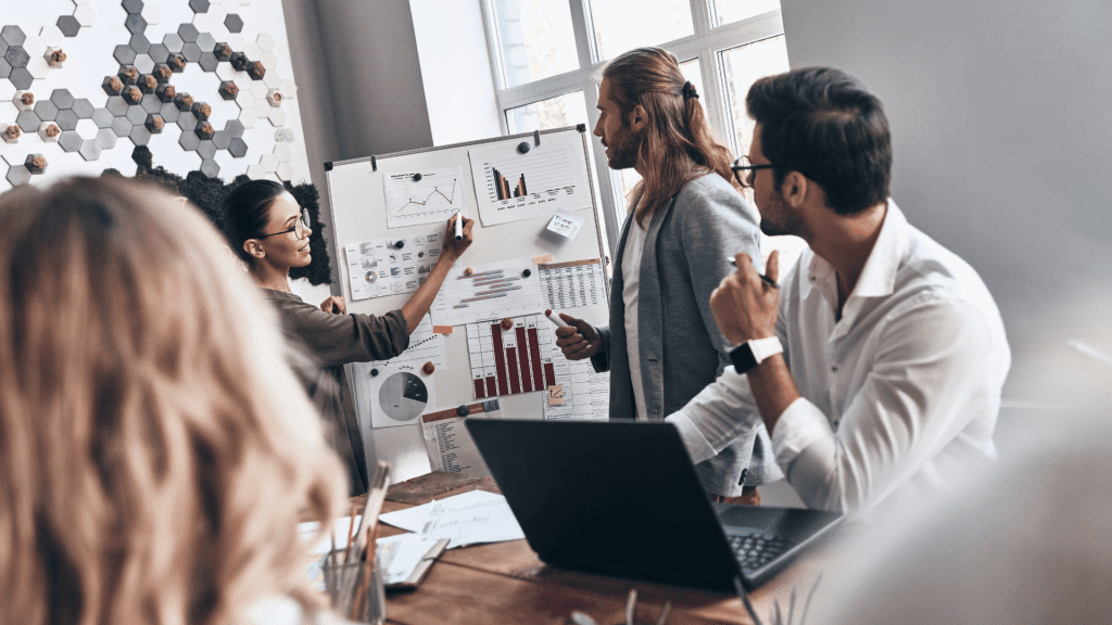 Equipe de inovação realiza assessment com gráficos e indicadores em quadro branco durante reunião corporativa