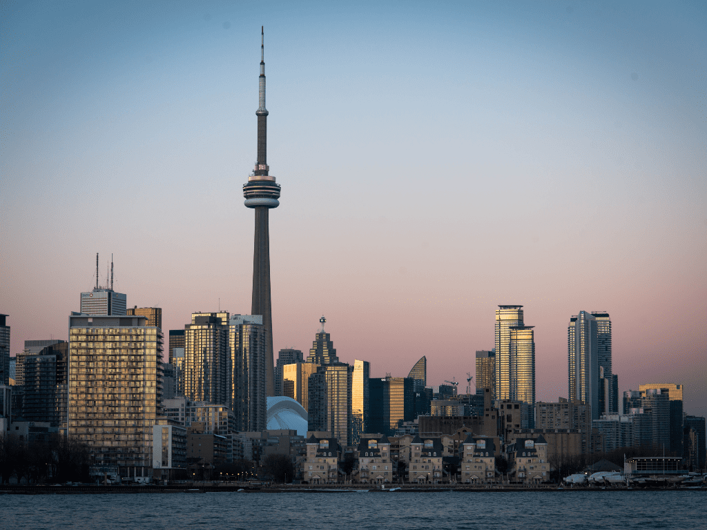 Skyline de Toronto ao entardecer com a CN Tower em destaque, representando o Canadá como centro de negócios e inovação.