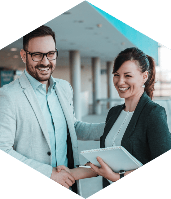 Dois profissionais sorridentes apertando as mãos em um ambiente corporativo, simbolizando parceria e colaboração nos negócios.