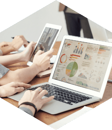 Profissionais utilizando laptop e tablet com dashboards e gráficos, representando acompanhamento contínuo de indicadores e resultados empresariais.