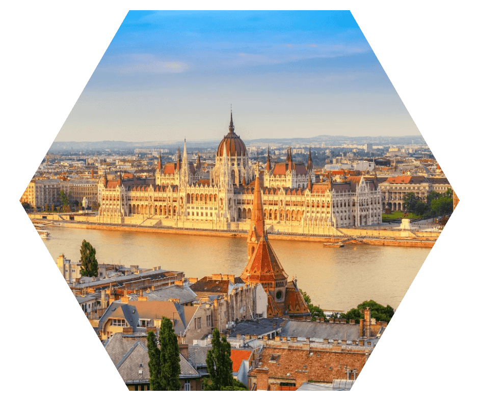 Vista do Parlamento de Budapeste iluminado pelo pôr do sol, às margens do rio Danúbio, com a cidade ao fundo