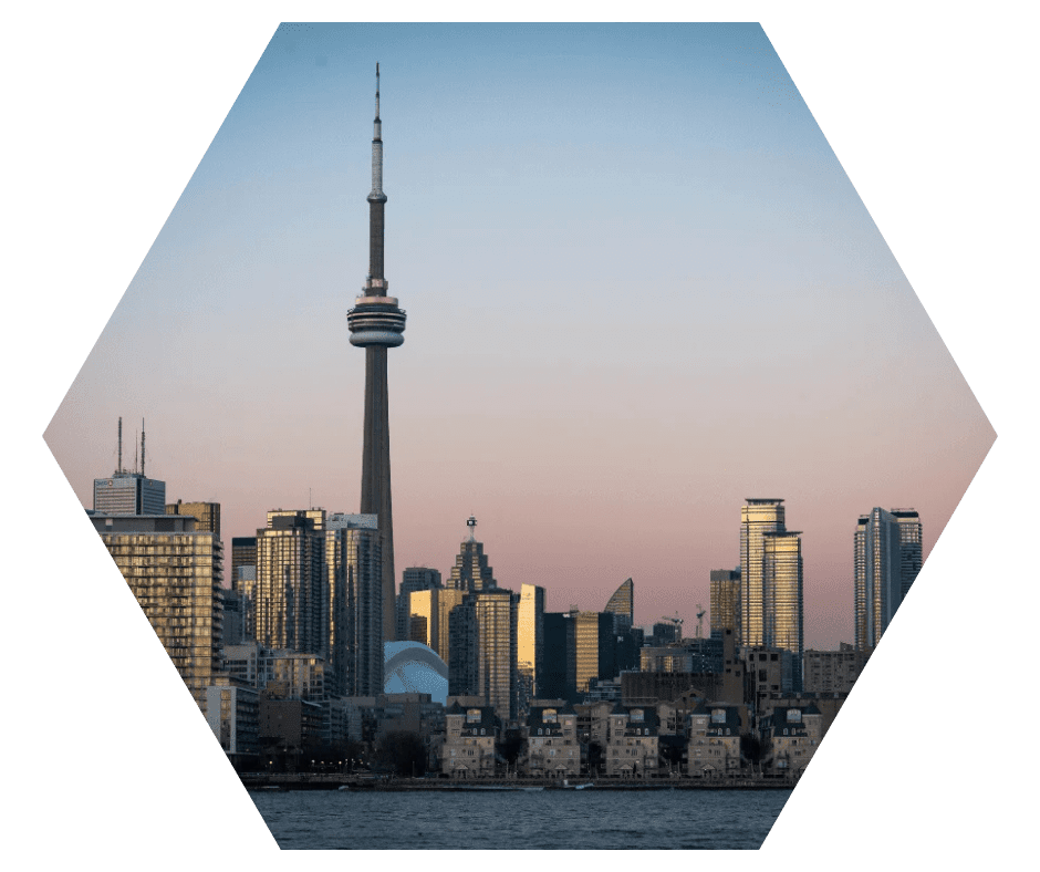 Vista do centro de Toronto ao entardecer, com a CN Tower em destaque e prédios iluminados sob um céu rosado